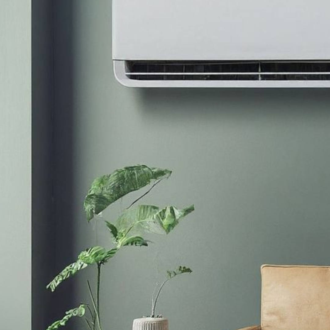 Foto de uma sala com um sofá marrom, uma planta e um ar condicionado do tipo split hi wall caseiro